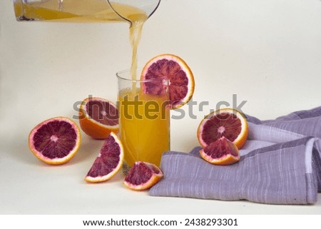 Orange juice in glass and slices of oranges around it