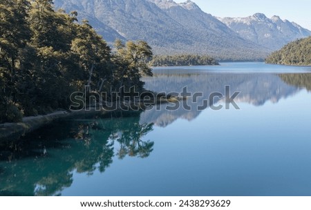 Calm and relaxing horizontal view of mountain range full of dense forests reflecting onto a lake's crystaline tranquil water wallpaper