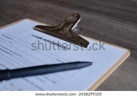 Pen and loan agreement form on a clipboard, preparation for filling and signing a form.
