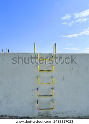 Yellow metal ladder for climbing, stairs, scoring goals, life ladder, hidden places, descent to the water, into the blue, yellow metal staircase climbing tool descent to water, descent to the water Royalty-Free Stock Photo #2438319023