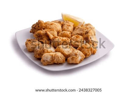 dish of dogfish in marinade with lemon wedge Royalty-Free Stock Photo #2438327005