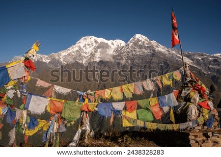 Nepali flag with beautiful view of Mt.Annapurna South (7,219 m) and Mt.Hiunchuli (6,441 m) seen from Mardi Himal view point in the Annapurna region of Nepal. Royalty-Free Stock Photo #2438328283