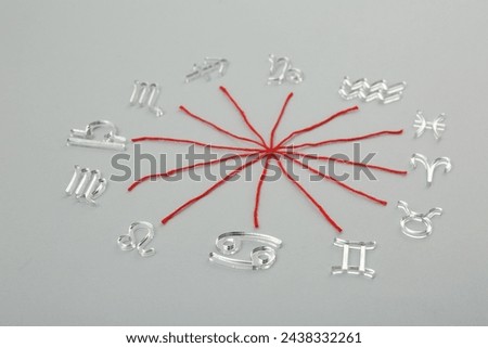 Zodiac compatibility. Signs and red threads on grey background Royalty-Free Stock Photo #2438332261