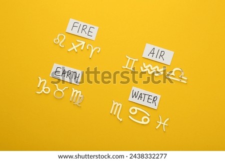 Zodiac triplicity. Four elements and corresponding signs on yellow background, flat lay