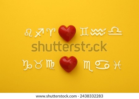 Zodiac compatibility. Signs with red hearts on yellow background, flat lay Royalty-Free Stock Photo #2438332283