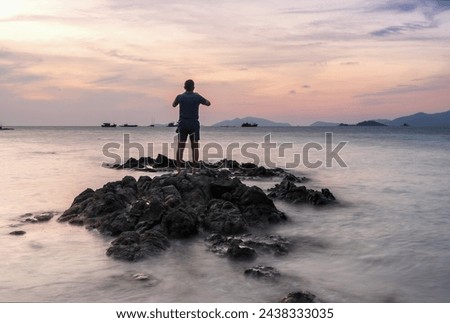 A westerner taking sunset picture at Lipe island, beautiful beach in Thailand. Silhouette of a person on the beach