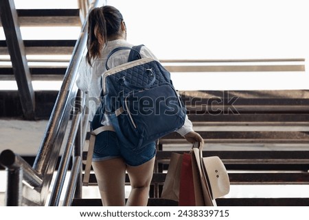 Horizontal photograph with copy space of an unrecognizable female customer, while traveling with her backpack; on his back going up and walking along some steps of some stores buying souvenirs