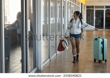 Photograph with copy space of a woman in her 20s traveling alone through Mexico, visiting local stores, walking with her shopping bags and suitcase while smiling looking at the prices