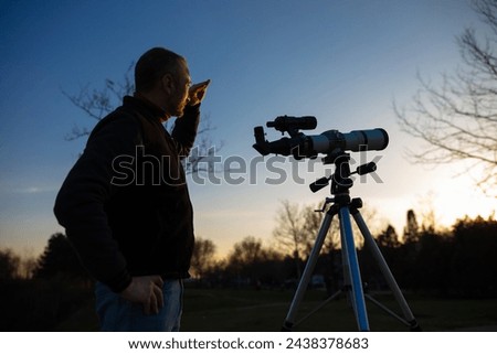 Amateur astronomer observing Sun eclipse and Sun with a telescope and special solar filter. Royalty-Free Stock Photo #2438378683
