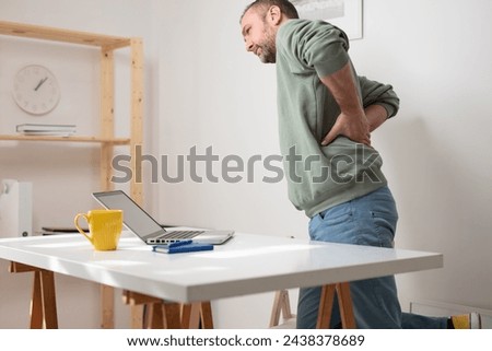Man with back pain while working on a laptop.