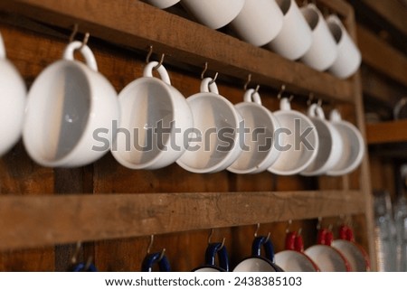 selective focus, many ceramic coffee mugs Hanging on a wooden wall In a country cafe