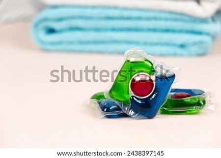 Laundry pods on beige background with soft towels