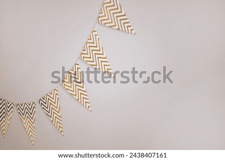 Festive chevron patterned bunting against a white wall. Minimalist design with copy space. Concept for event decoration, celebratory atmosphere.