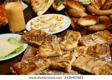 A wooden table is covered with a variety of sumptuous food dishes, including meats, vegetables, fruits, and desserts. Royalty-Free Stock Photo #2438407885