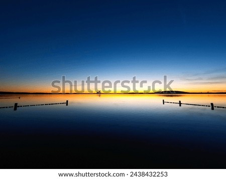 Sunset at Lake Störmthal. Sun creates thin yellow to red light streaks on the horizon. the rest of the picture is deep blue. Unique atmosphere on a lake near Leipzig.