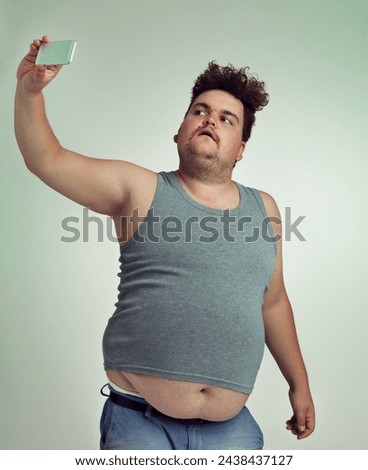 Selfie, fashion and plus size man in studio posing with casual, trendy and cool outfit with stomach. Style, serious and crazy male person with photography picture isolated by gray background.