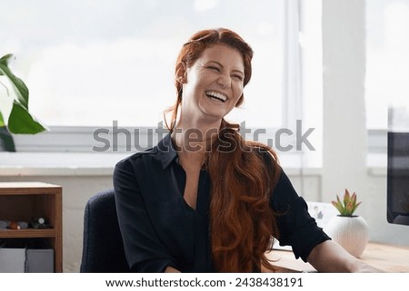 Businesswoman, laughing and office desk as entrepreneur at tech startup for small business, professional or funny. Female person, smile and confidence for company growth or humor, joke or workplace Royalty-Free Stock Photo #2438438191