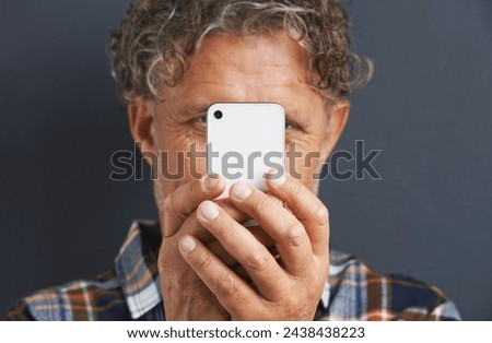 Mature, man and capture a photo with phone in studio and learning about photography on dark background. Smartphone, recording or filming a video for post online to social media for memory of picture