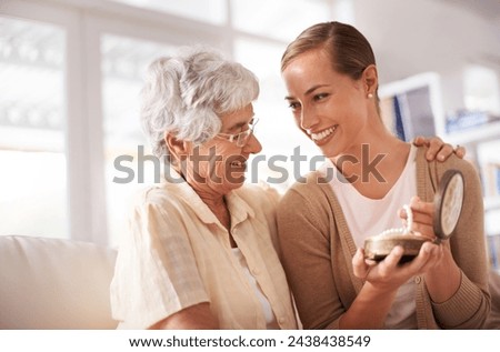 Gift box, necklace and senior mother with woman on sofa for present, giving and surprise in living room. Family, pearls and happy daughter with mom heirloom for celebration, birthday and bonding Royalty-Free Stock Photo #2438438549