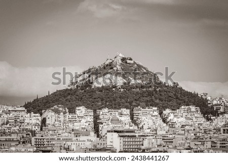 Old black and white picture of the Likavittou Lykabettus and the Holy Church of Saint Isidore with blue cloudy sky in Greece's capital Athens in Greece.