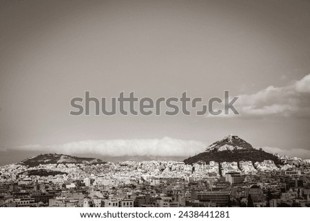 Old black and white picture of the Likavittou Lykabettus and the Holy Church of Saint Isidore with blue cloudy sky in Greece's capital Athens in Greece.