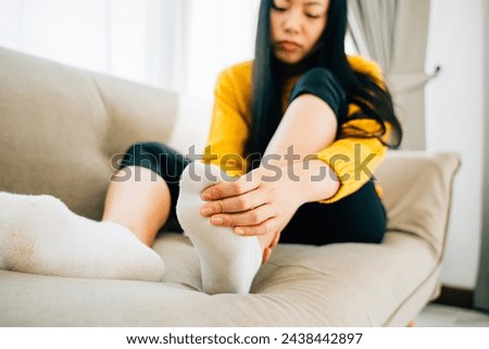 Depicting health care concept, a woman sitting on a sofa massaging her painful foot with a highlighted area indicating pain. Emphasizing recovery reflexology and relief from discomfort.