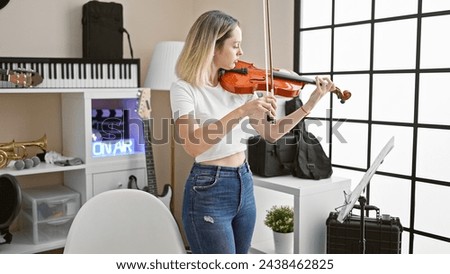 Young blonde woman musician playing violin at music studio