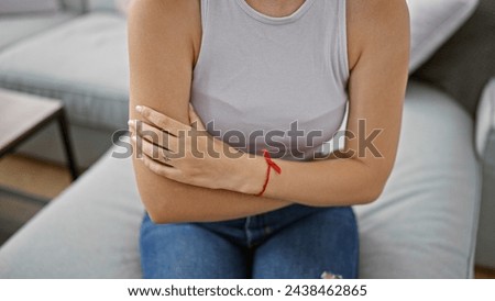 Young blonde woman sitting on sofa with arms crossed gesture at home
