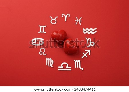 Zodiac signs and hearts on red background, flat lay
