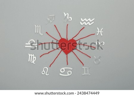 Zodiac compatibility. Signs, red heart and threads on grey background, flat lay Royalty-Free Stock Photo #2438474449