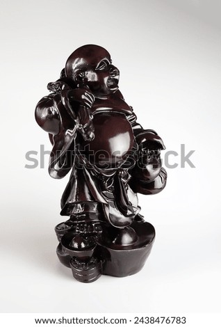 Figurine of a laughing Buddha on a white background. The title of a being who has achieved the highest state of spiritual perfection