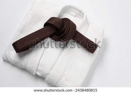 Brown karate belt and kimono on white background, top view Royalty-Free Stock Photo #2438480815