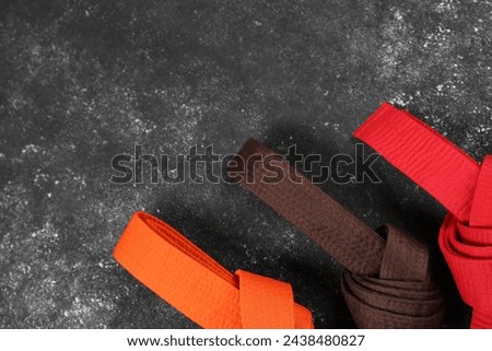 Colorful karate belts on gray background, flat lay. Space for text Royalty-Free Stock Photo #2438480827