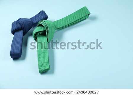 Colorful karate belts on light blue background, space for text Royalty-Free Stock Photo #2438480829