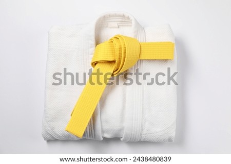 Yellow karate belt and kimono on white background, top view Royalty-Free Stock Photo #2438480839