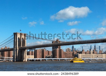 bright yellow water taxi sails under the Brooklyn Bridge 