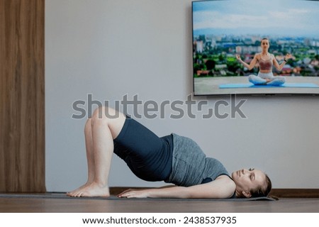 Pregnant woman exercing yoga at home. Lies on his back and lifts up
