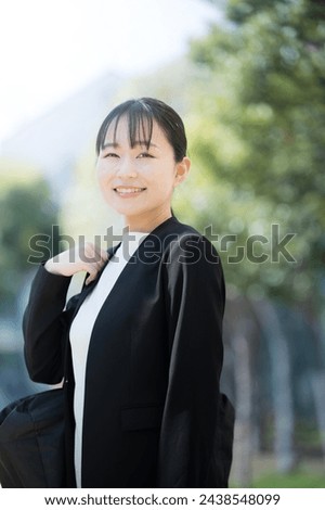 Young Japanese woman in suit with bag, either on business or looking for a job. Vertical photo.