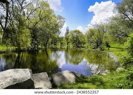 Picturesque scene of a still pool of water in a verdant setting with bright skies at the Dominion Arboreturm in Ottawa,Ontario,Canada Royalty-Free Stock Photo #2438552357