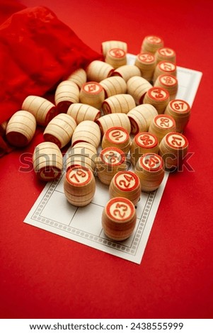 Wooden bingo kegs, on a red background in a red bag, for playing bingo. A way to spend time at home. A game of chance, card with numbers. . High quality photo