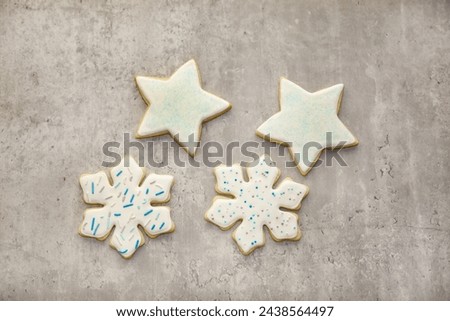 Snowflake and star shaped sugar cookies with royal icing and sprinkles on top.