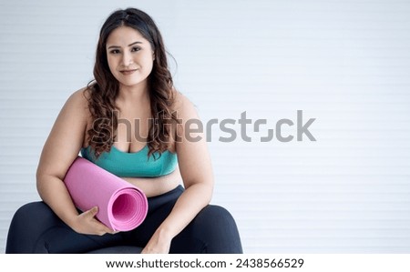 Portrait of fat asian woman sitting with yoga mat in hand with free space