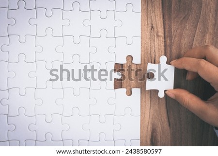 Closeup hand of woman connecting jigsaw puzzle. Business solutions, success and strategy concept.  Royalty-Free Stock Photo #2438580597