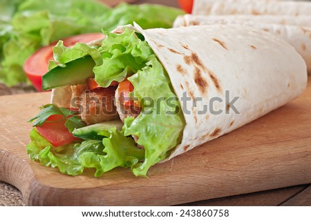 Fresh tortilla wraps with chicken nuggets and vegetables on plate