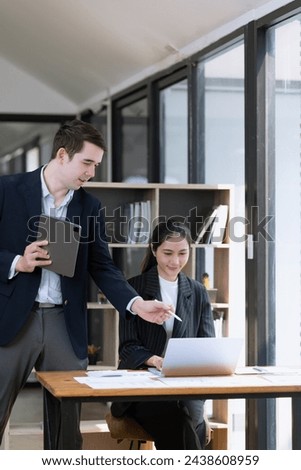 Photo of two business people using laptop computer and working together in the office desk.