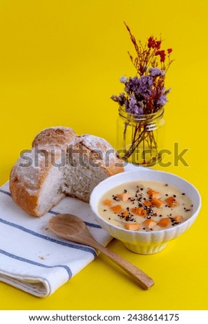 Breakfast: onion soup with sausage and black pepper in a white bowl, wooden spoon, eaten with bread.  on the yellow scene
