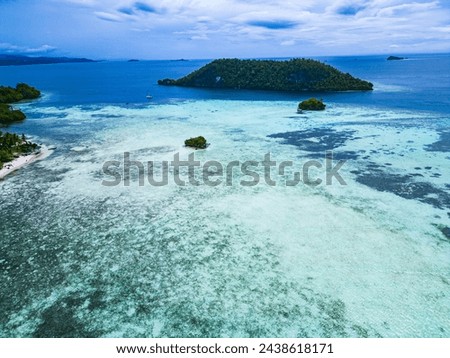 Drone photo of the tropical island of Frewen, located in the middle of the ocean and surrounded by coral reefs