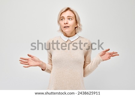 Confused young woman shrugging her shoulders with a puzzled expression, isolated on a light background.