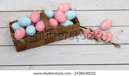 Basket with Easter eggs on a white wooden board.