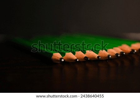 France, March 4, 2024. Wooden pencils or paper pencils or graphite pencils designate this drawing or writing instrument. painted in green with their grey mines, they are placed on a black background.  Royalty-Free Stock Photo #2438640455